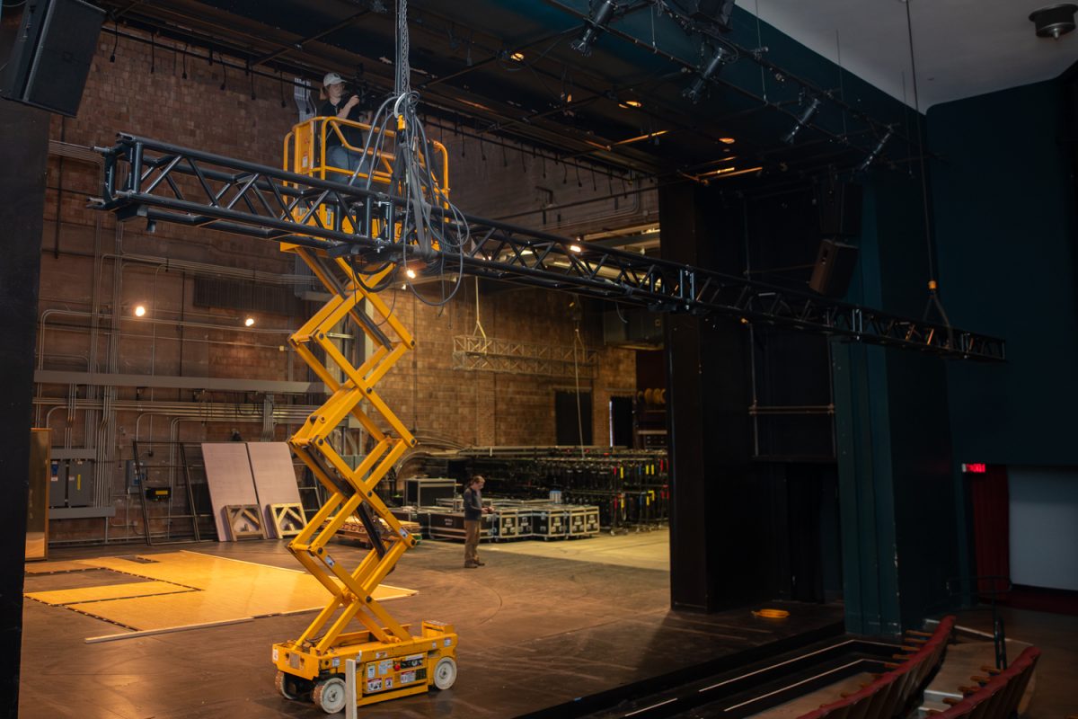 An electrical crew member raises scaffolding to work on the lighting system above at the University of Iowa Theatre Building in Iowa City, Iowa on Dec. 1, 2025. The department is currently working on sets for their upcoming show How to Defend Yourself which will have its first performance on February 6, 2026.