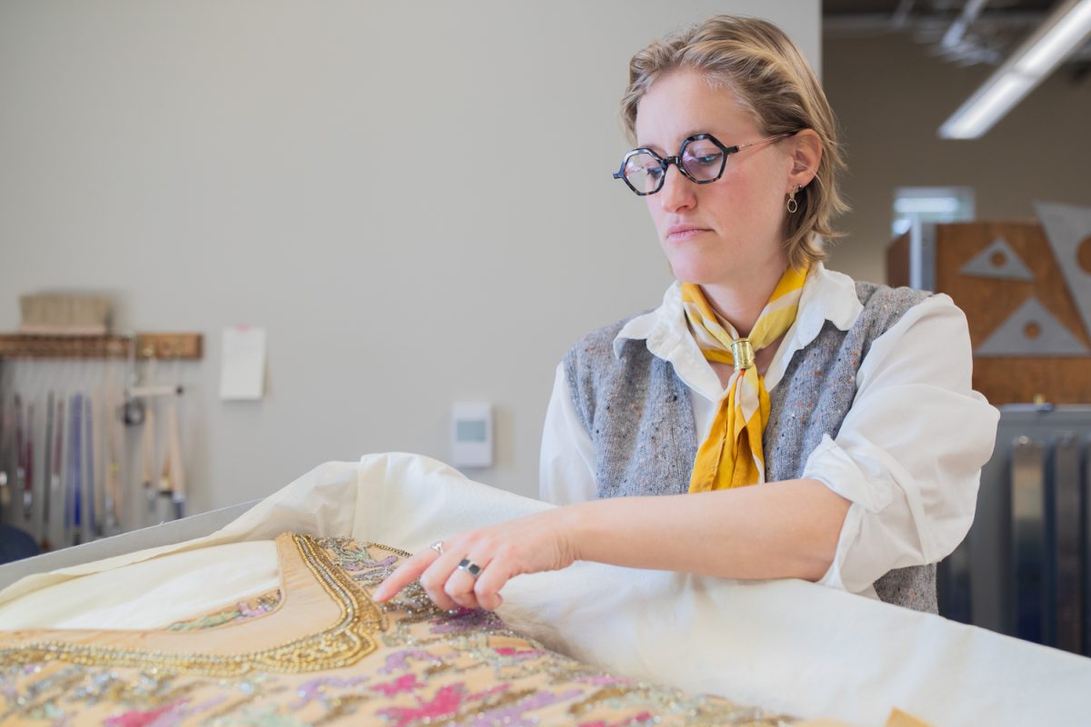 Archivist Zoe Webb points to embedding on the Indiana Briton Flapper Dress in the Main Library in Iowa City, Iowa on Monday, Dec. 15, 2025. Webb works as the collections Care Technician for the UI Conservation Lab.