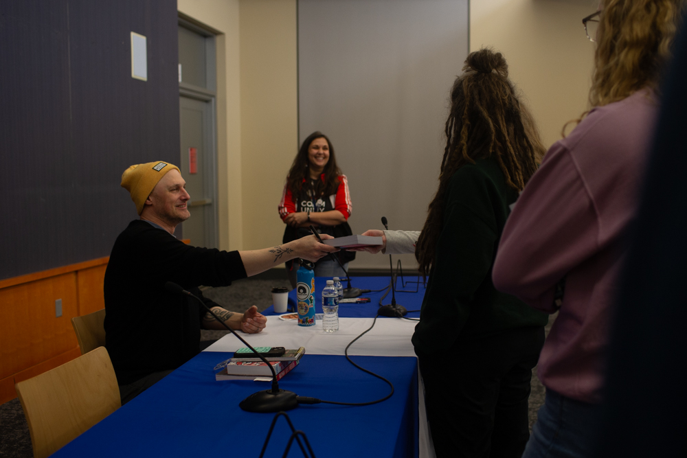 Jarrett Dapier hands a signed book to a fan during a book event at the Iowa City Public Library on Thursday, Feb. 5th, 2026. (Sal Yang/The Daily Iowan)
