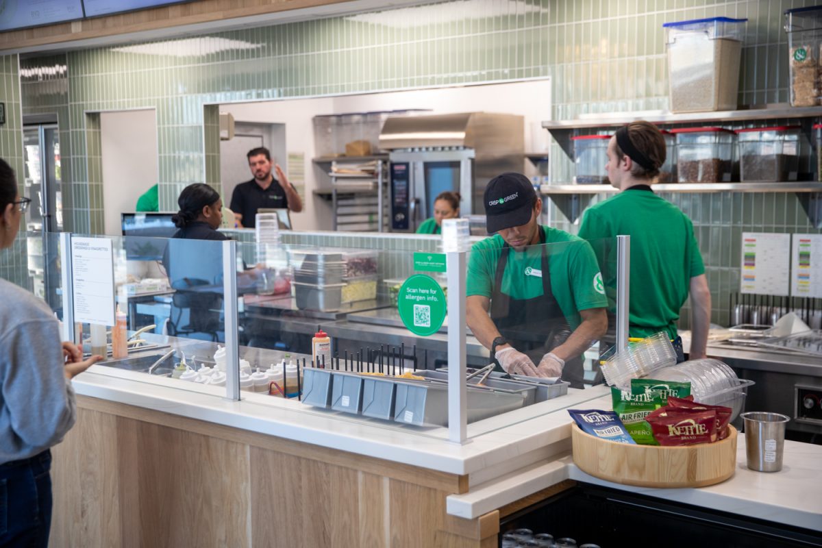 A worker at Crisp and Green helps a customer make their order on Wednesday, Feb. 11, 2026. Crisp and Green is a healthy fast food restaurant where customers can customize and build their own wraps, bowls, and salads.  (Danny Enright/The Daily Iowan)