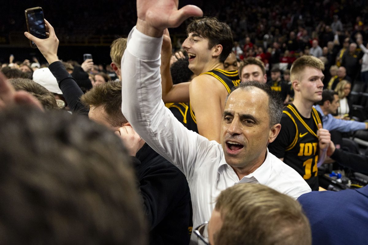 Iowa head coach Ben McCollum high-fives fans as they storm the court and celebrate with the team after a basketball game between the Iowa Hawkeyes and the No. 9 Nebraska Cornhuskers at Carver-Hawkeye Arena on Tuesday, Feb. 17, 2026. The Hawkeyes upset the Cornhuskers, 57-52. (Samantha DeFily/The Daily Iowan)