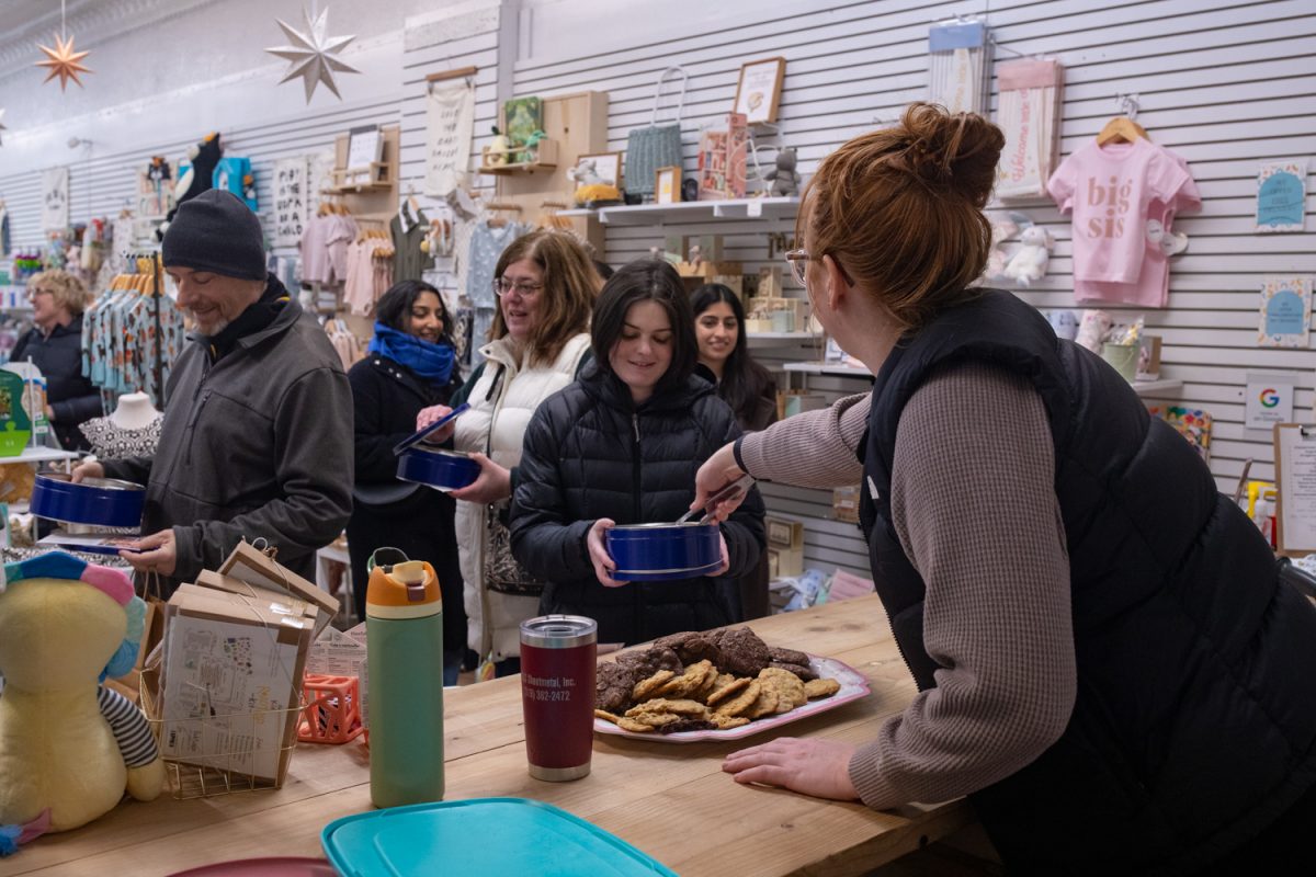 A worker at 223 Baby Co. hands out cookies to shoppers during the 2026 Cookie Crawl throughout downtown Iowa City, IA on Saturday, Feb. 28, 2026. Over a hundred shoppers stopped by 16 participating stores to collect a variety of different cookies.