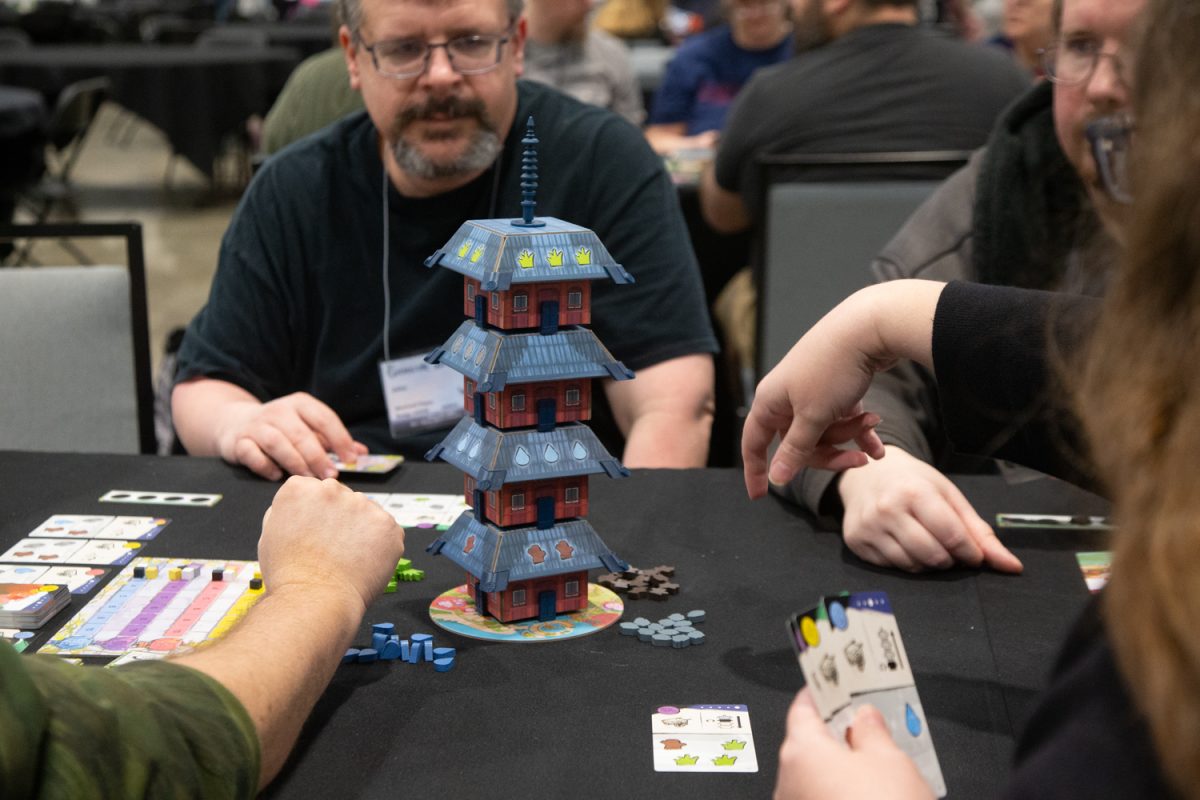 Four players play Four Gardens and twirl the tower according to the cards they put down, at Gamicon Bromine, Coralville, IA, on Friday, Mar. 6, 2026. Players can play games from the Game Library provided by Gamicon or join games hosted by game developers.(Sal Yang/The Daily Iowan)