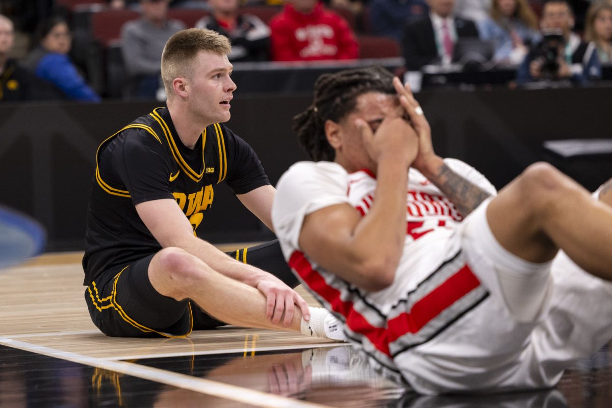 Iowa guard Bennett Stirtz sits on the ground as Ohio forward Devin Royal holds his face during a basketball game between the No. 9 seed Iowa Hawkeyes and the No. 8 seed Ohio State Buckeyes at the United Center in Chicago, Illinois on Thursday, March 12, 2026. The Buckeyes defeated the Hawkeyes, 72-69. (Samantha DeFily/The Daily Iowan)