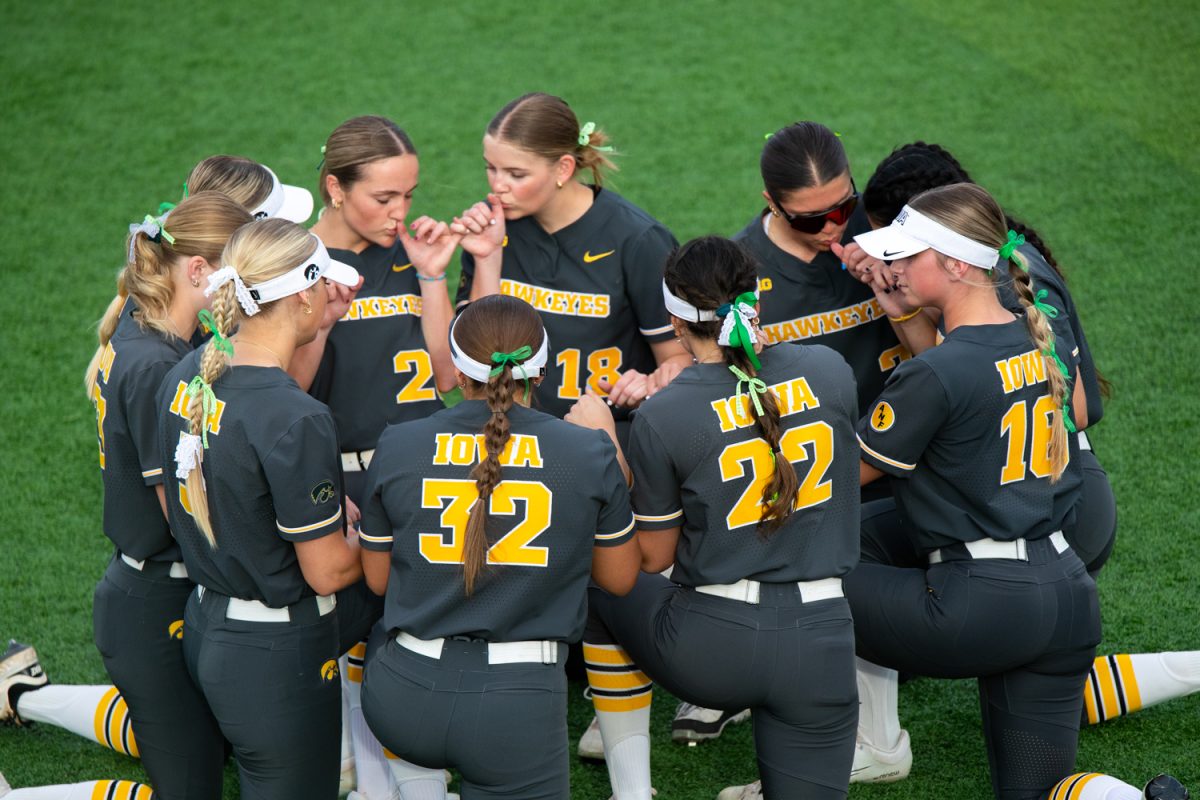 The Iowa softball team huddles before the game between the Iowa Hawkeyes and the Minnesota Gophers in Iowa City at Bob Pearl Field on Friday, March 20, 2026. This is the game opener for the Hawkeyes and their new head coach Stacy May-Johnson. The Gophers beat the Hawks 2-0 to start off the softball season. (Travis Crabb / The Daily Iowan)