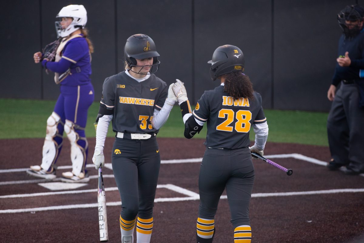Iowa left fielder Echo Mattiello high-fives third basemen Avery Jackson after Mattiello struck out at the softball game between Iowa and No. 16 Washington on Friday, March 27, 2026. Mattiello had three putouts against Washington. The Huskies handed the Hawks their biggest defeat of the season so far with a 16-7 win over Iowa. (Travis Crabb/The Daily Iowan)