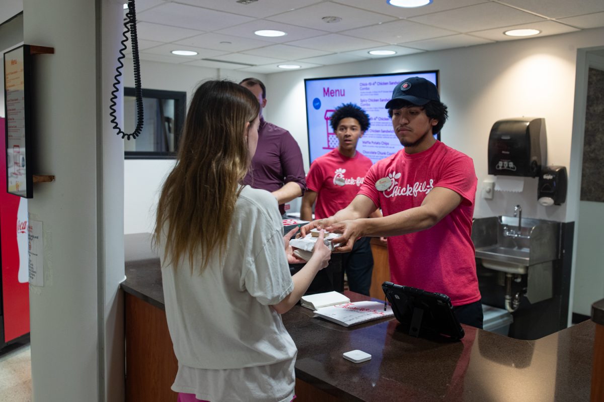 JT Baker and Job Arrazola serve a customer at the newly-opened Chick-Fil-A in the Iowa Memorial Union on Monday, March 30, 2026. The Chick-Fil-A has taken the place of Old Gold Ice Cream and had its grand opening on Monday. (Ava Neumaier / The Daily Iowan(