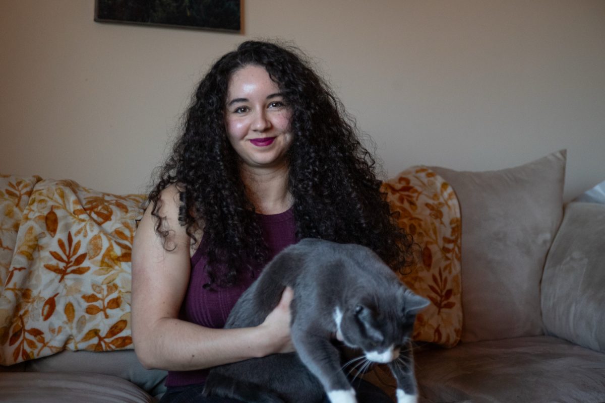 Author Tatiana Schlote-Bonne poses for a photo with one of her cats in her home on January 23, 2026. Schlote-Bonne is currently awaiting the release of her third book What Feeds Below. She says that her cats are some of her best writing companions (Annika Nelson/Daily Iowan).
