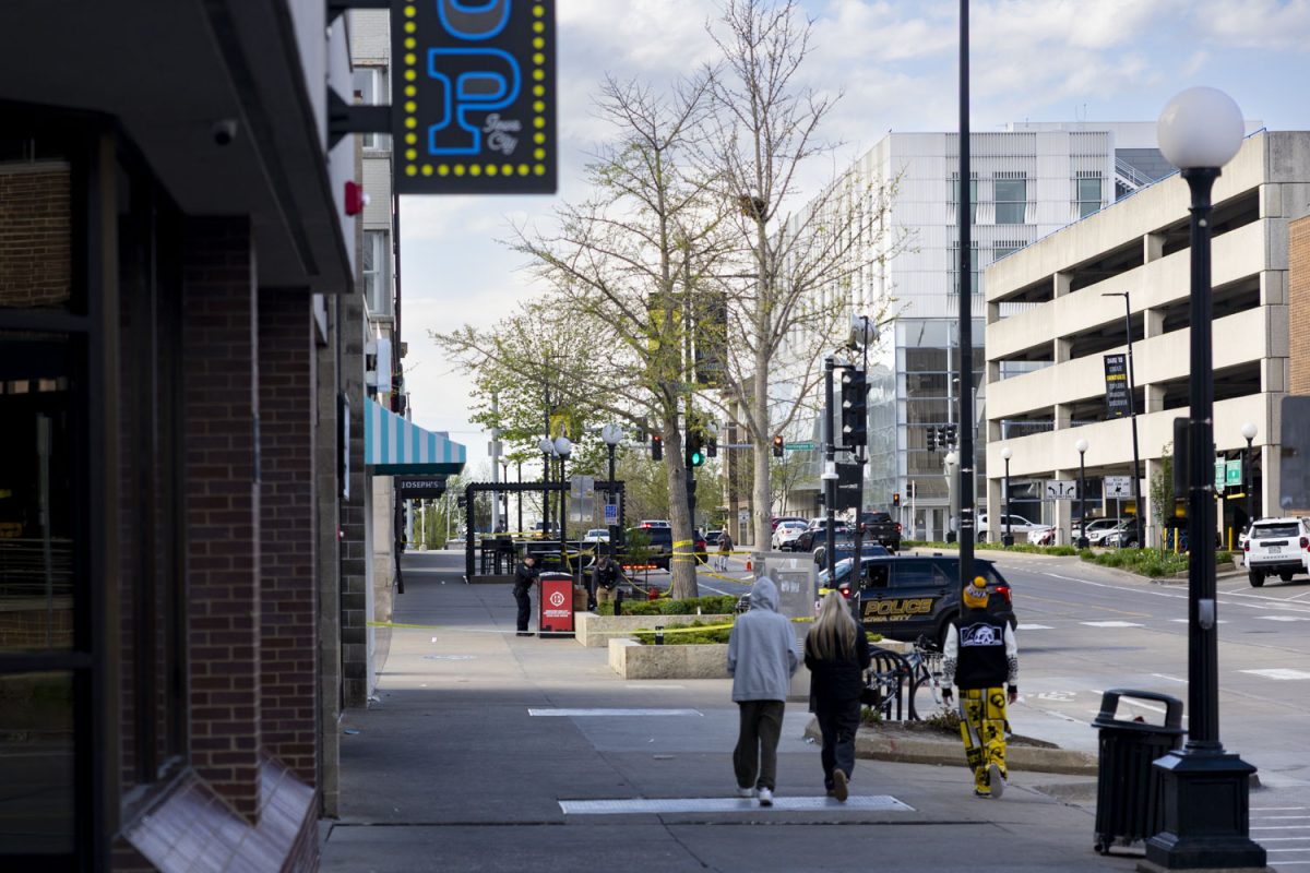 People walk past a crime scene in the Pedestrian Mall Iowa City, Iowa on Sunday, April 19, 2026. Three students from the University of Iowa were injured in a shooting early Sunday morning.(Samantha DeFily/The Daily Iowan)