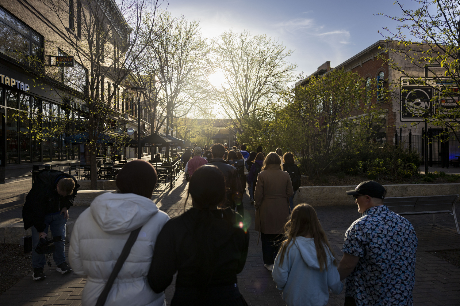 Attendees walk towards the Pedestrian Mall during an Iowa City peace vigil at the Pedestrian Mall in Iowa City on Monday, April 20, 2026. The vigil follows a shooting on the morning of April 19 that injured three University of Iowa students. (Samantha DeFily/The Daily Iowan)