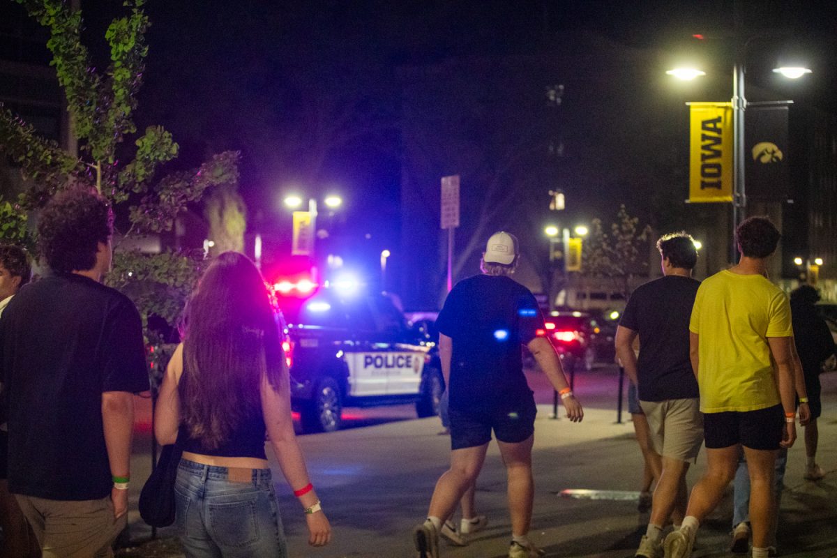 Civilians walk past a patrol car in downtown Iowa City on Saturday, April 26, 2026. The Iowa City Police Department has added extra foot patrol to keep civilians safe after a shooting on the Pedestrian Mall in Iowa City on April 19. (Sarah Hughes/The Daily Iowan)