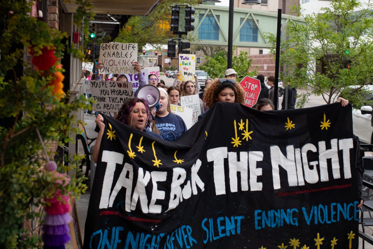 Attendees march through downtown Iowa City during Take Back the Night, an annual march and protest to raise awareness for sexual assault survivors on Tuesday, April 28, 2026. The event is in its 50th year, and was attended by around one hundred participants. Signs were available to march with, as were stickers and snacks from feminist organizations on campus. (Ava Neumaier / The Daily Iowan)
