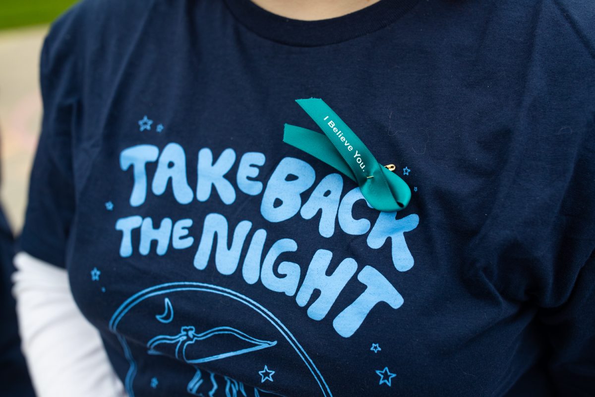 A pin is seen on a volunteer’s shirt during Take Back the Night, an annual march and protest to raise awareness for sexual assault survivors in Iowa City on Tuesday, April 28, 2026. The event is in its 50th year, and was attended by around one hundred participants. Signs were available to march with, as were stickers and snacks from feminist organizations on campus. (Ava Neumaier / The Daily Iowan)
