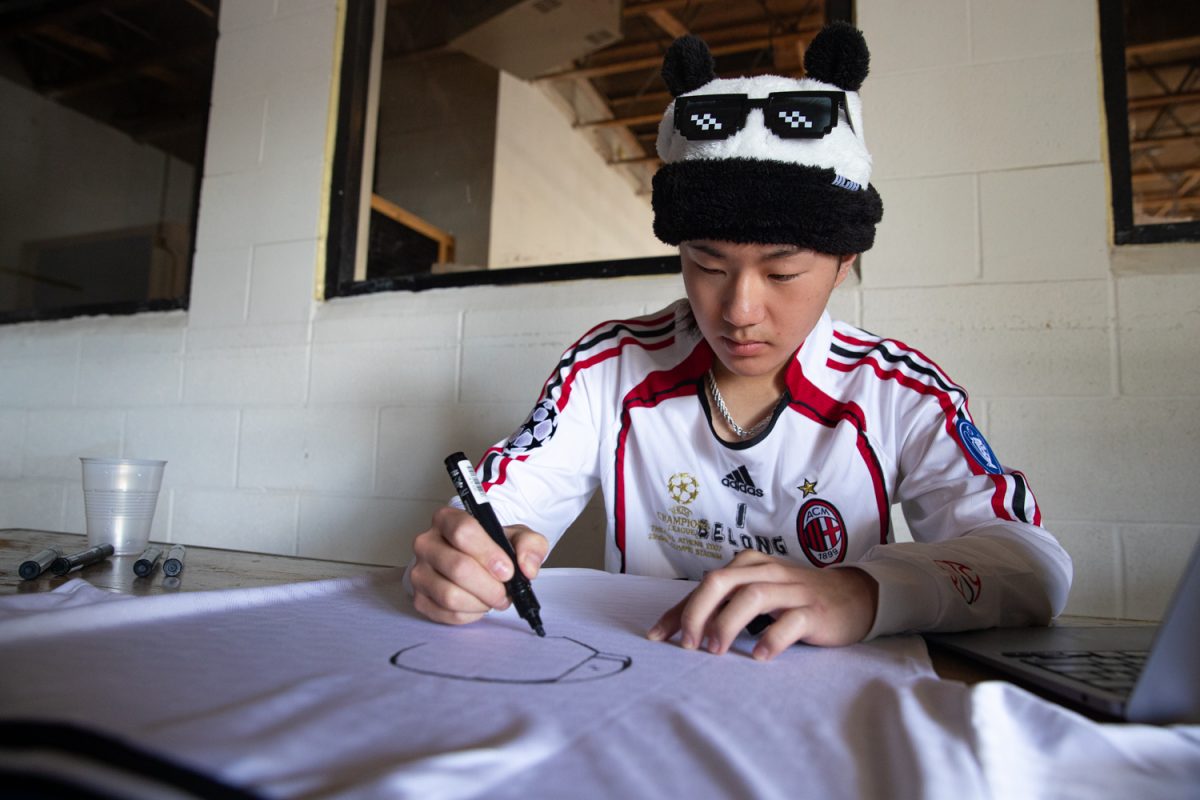 Max Jiang draws on a shirt during the Iowa City Beyond Fashion Fest 2 at the Wright House of Fashion on Saturday, May 2, 2026. This is the second year of the Fashion Fest, which runs from May 1-2 with fashion walks, markets, panels, and parties. Jiang has been making shirt art for a month before hosting a stand at the vendor’s market.