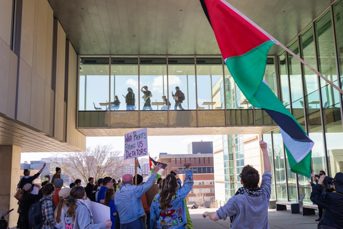 Members of Iowa City Action for Palestine wave at the crowd of protestors below during a Pro-Palestine demonstration at the University of Iowa on April 10, 2026. Iowa City Action for Palestine is protesting the engineering college’s partnership with American Ordinance and these members are delivering a petition with 600+ signatures to the Director of Career Services to demand AO be removed from career fairs.