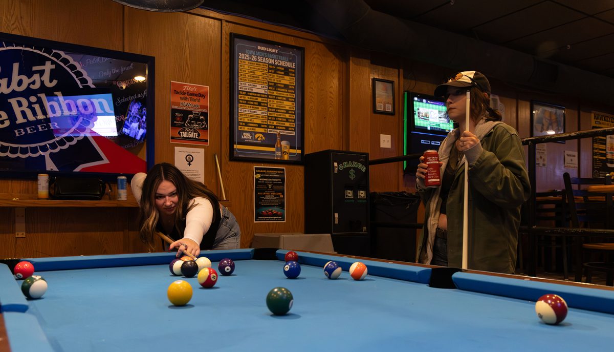 Aly Hurley playing pool with Mia Chiligiris at Joes Place in Iowa City on Tuesday, Mar. 10, 2026. Chiligiris is a friend of Hurleys and visiting for the week, so the two got together to hang out, play pool, and catch up with one another. The two used to work together but haven't been able to see each other due to Chiligiris living in Chicago and Hurleys busy schedule. (Jolie Archer / SJMC)